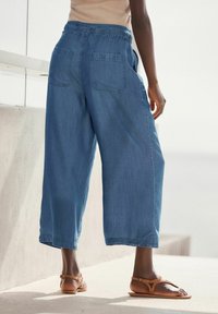 Denim culotte-housut ovat varustettu joustavalla vyötäröllä, kahdella takataskulla, rentolla istuvuudella ja vaaleansinisellä värillä, joka on sileä.