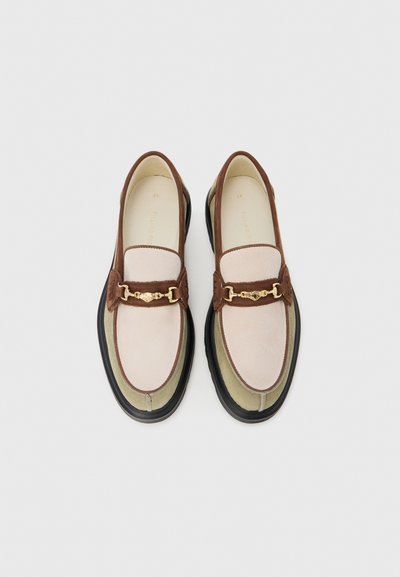 Loafers i lyserød og brun suede med en guld kæde accent, der har en kontrasterende sort gummisål og rund tå design.