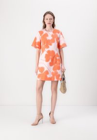 Rochie cu mânecă scurtă, albă, cu un model floral mare portocaliu, având un decolteu rotund și o siluetă ajustată. Asortată cu sandale cu toc bej.