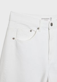 Jeans in denim bianco con taglio dritto, tasche frontali, hardware argentato e etichetta che indica la taglia 38. Il tessuto ha una texture liscia.