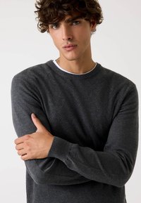 Maglione a maglia grigio scuro con motivo a rombi, collo a giro e polsini a coste. Texture morbida con un design aderente.