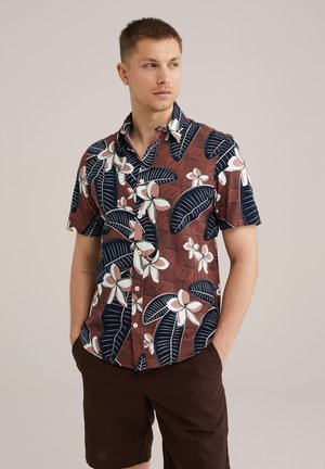 Chemise à manches courtes avec un fond brun orné de fleurs blanches et de motifs de feuilles bleu marine, fabriquée à partir d'un tissu léger et dotée d'un boutonnage sur le devant.