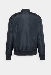Veste bomber en satin noir avec col, poignets et bas côtelés, vue de dos sur fond blanc uni.