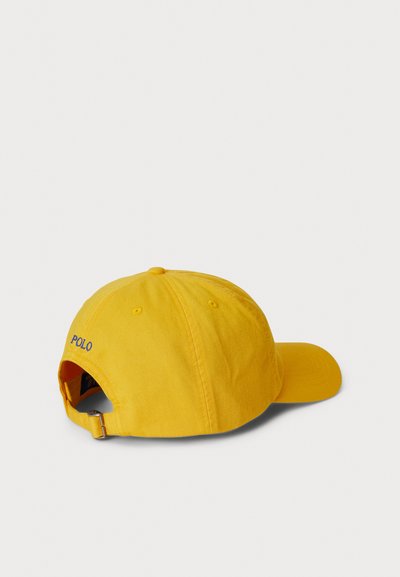 Boné de baseball amarelo de algodão com aba curva, tira ajustável e "POLO" bordado na parte de trás. Tecido texturizado, design casual.