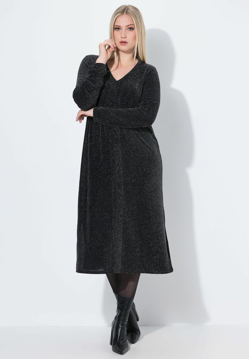 Schwarzes, langärmliges Kleid mit einem V-Ausschnitt, aus einem glitzernden Material, knielang, mit einem lockeren Schnitt und seitlichen Schlitzen.