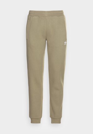 Beige joggingbroek met elastische tailleband, zijzakken, enkelboorden en een klein wit Adidas-logo op het bovenste linker dijbeen.
