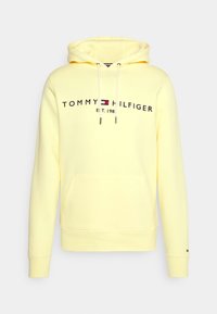 Felpa leggera gialla di Tommy Hilfiger con tasca frontale, cordini bianchi e logo con emblema della bandiera sul petto.