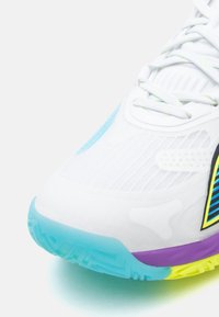 Hvid atletiksko med tekstureret hvid overdel, lyseblå sål, lilla og gule detaljer samt diagonale sorte og blå striber.