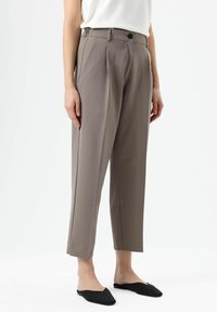 Grijze, op maat gemaakte broek met een hoge taille, voorplooien en zijzakken. Voorzien van een enkele knoopsluiting en smalle, cropped pijpen.