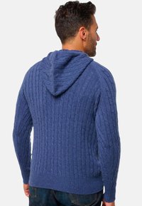 Dunkelblaues Strick-Hoodie mit gerippten Bündchen und Saum. Es zeigt ein strukturiertes Muster und verfügt über eine Kapuze für zusätzliche Wärme.