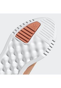 Shoe sole with white rubber, featuring a textured surface and an orange accent with the Adidas logo. Details include rounded nodules and ridges.