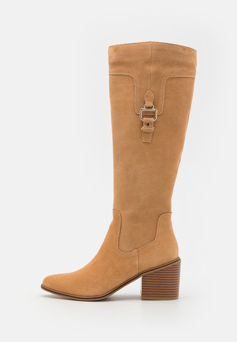 Knee-high tan suede boots with a square toe, textured heel, and a decorative strap with buckle detail. Featured stitching accents.