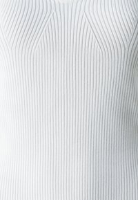 Top bianco a coste con righe verticali, scollo rotondo e superficie testurizzata con dettagli delle cuciture sulle spalle.