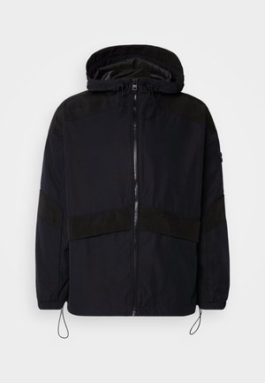 Μαύρο μπουφάν με κουκούλα, που διαθέτει φερμουάρ και αντίθετες ματ υφές στους ώμους και το στήθος. Ρυθμιζόμενο κορδόνι στο στρίφωμα.