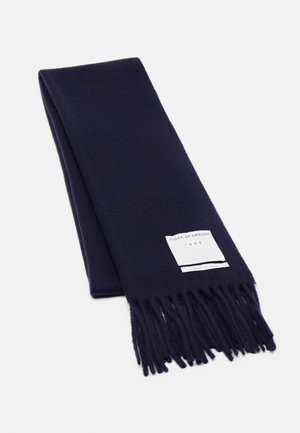 Marineblåt uldtørklæde med frynser i enderne og et hvidt mærke med teksten "Tiger of Sweden 1903, Made in Italy" på ensfarvet baggrund.