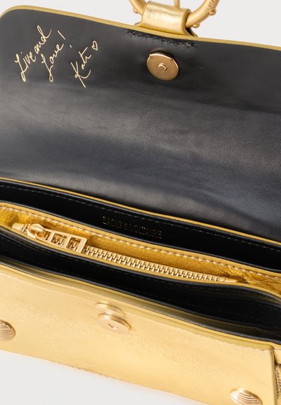 Arany és fekete bőr pénztárca belseje arany cipzárral, mágneses patenttal, és kézzel írt üzenettel a fedél belső oldalán: "Élj és szeress! Kate".