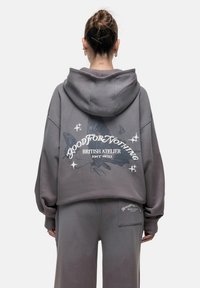 Felpa grigia oversize con un grande design stampato che presenta farfalle e testo sul retro. Tessuto liscio e vestibilità comoda.