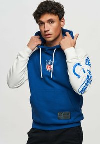 Blue and white hooded sweatshirt with NFL logo. Features a kangaroo pocket, white sleeves with blue graphics, and textured fabric.