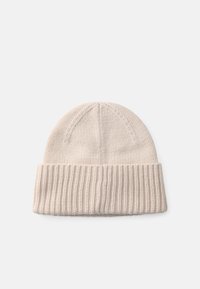 Strikket lue i lys beige, med ribbestrikket mansjett og en jevn tekstur på kroppen, samt en avrundet topp og diskret sømdetaljer.