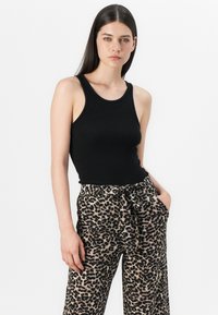 Top en maille noir à côtes associé à un pantalon large en imprimé léopard, doté d'une ceinture à nouer et de poches latérales. Design simple et ajusté.