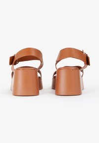 Sandali platform marroni con una fascia larga e fibbia regolabile, caratterizzati da una texture liscia e design con tacco quadrato.