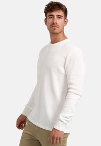 Weißer gestrickter Pullover mit strukturierten horizontalen Streifen. Rundhalsausschnitt, lange Ärmel, lockerer Schnitt. Glattes Material mit gerippten Bündchen und Saum.