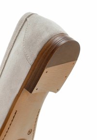 Talons de chaussure en daim gris clair avec forme arrondie. Accent en bois à la base, présentant un détail en cuir cousu et une finition lisse.