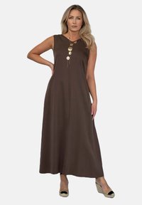Brązowa, bezrękawna sukienka maxi z przednią listwą i złotym okrągłym naszyjnikiem akcentującym. Gładki materiał, krój w literę A i długość do kostek.
