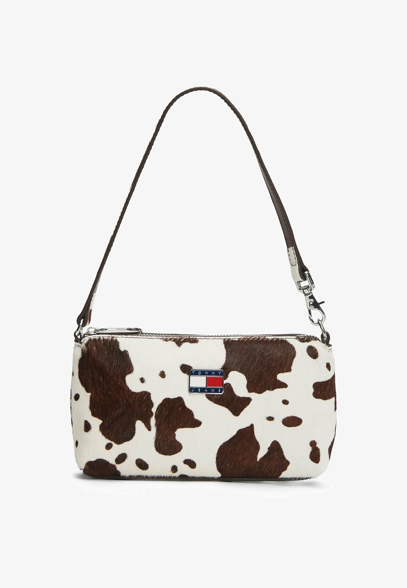 Lille rektangulær håndtaske med brunt og hvidt ko-hud mønster, kort mørkebrun rem og Tommy Jeans logo på forsiden.