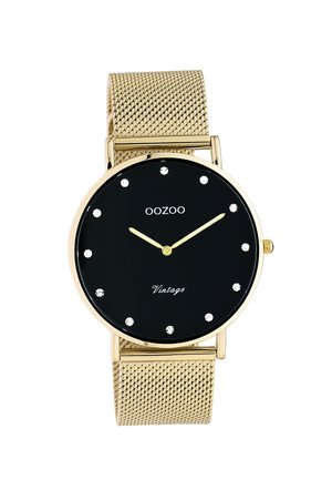 Gold-tone metal mesh wristwatch with a round black face, gold hands, and six crystal hour markers. Features a "Vintage" inscription.