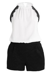 Top corto blanco sin mangas con detalles de encaje negro en los hombros, combinado con pantalones cortos texturizados negros con bolsillos frontales y una cinturilla lisa.