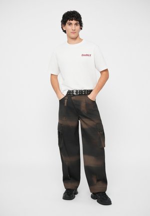 Λευκό βαμβακερό T-shirt με κόκκινο κείμενο "Double V", σε συνδυασμό με μαύρο cargo παντελόνι με καφέ κλίμακα και πολλές τσέπες. Περιλαμβάνεται μαύρη ζώνη.