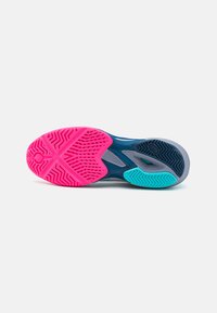 Semelle de chaussure présentant un motif de traction avec des sections rose, turquoise et grise. Le caoutchouc texturé offre une adhérence avec des motifs en zigzag.