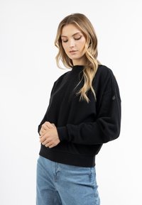 Mustapaitainen crewneck-sweatshirt, jossa on pitkät hihat ja pehme�ä kangas. Varustettu ribbatulla hihansuilla ja helman reunalla sekä pienellä logolla vasemmassa hihassa.