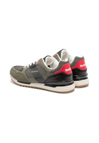 Baskets en suède et mesh vert avec accents noirs, dotées d'un patch de talon rouge et de lacets blancs. Semelle en caoutchouc avec grip texturé.