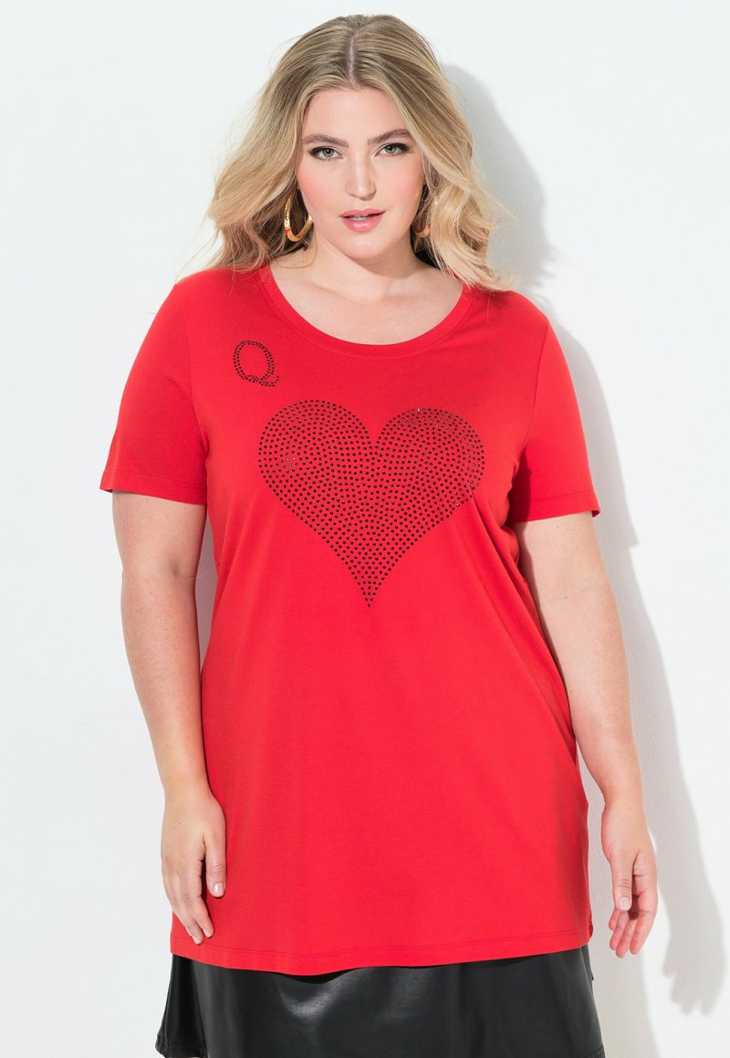 Rød T-shirt lavet af bomuld med korte ærmer, prydet med et stort hjerte design i sorte rhinsten og et lille sort 'Q' i det øverste venstre hjørne.