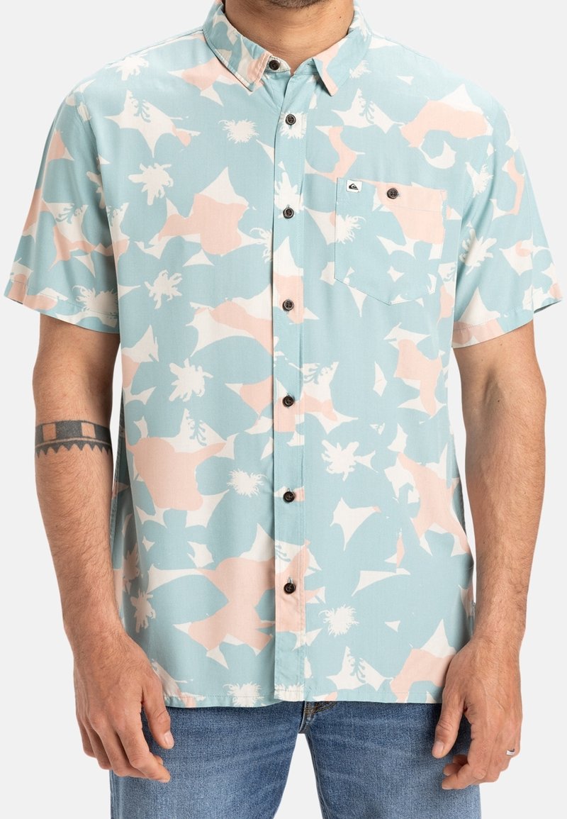Košile s krátkým rukávem v světlé modré barvě s abstraktním růžovo-bílým vzorem; má límec na knoflíky a náprsní kapsu s logem.