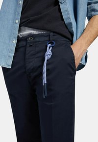 Pantaloni navy con una texture liscia, dotati di una cintura in corda blu intrecciata. Progettati con chiusura a bottone e tasche laterali.