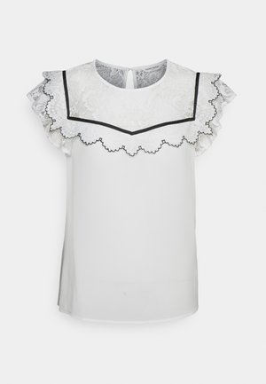 Blusa blanca de manga corta con canesú de encaje y bordes con volantes, acentuada por un ribete negro con borde festoneado alrededor del escote y las mangas.