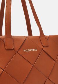Brun läder tote-väska med ett kviltat mönster, platta handtag och en guldlogga "Valentino" präglad på framsidan.