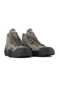 High-top olive green sneakers with rubber toe caps, textured black outsoles, and brown laces. Features branded tongue and side details.