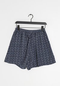 Shorts à motifs bleus sur un cintre noir. Le tissu présente de petites fleurs blanches, rouges et marines, avec une taille élastique.