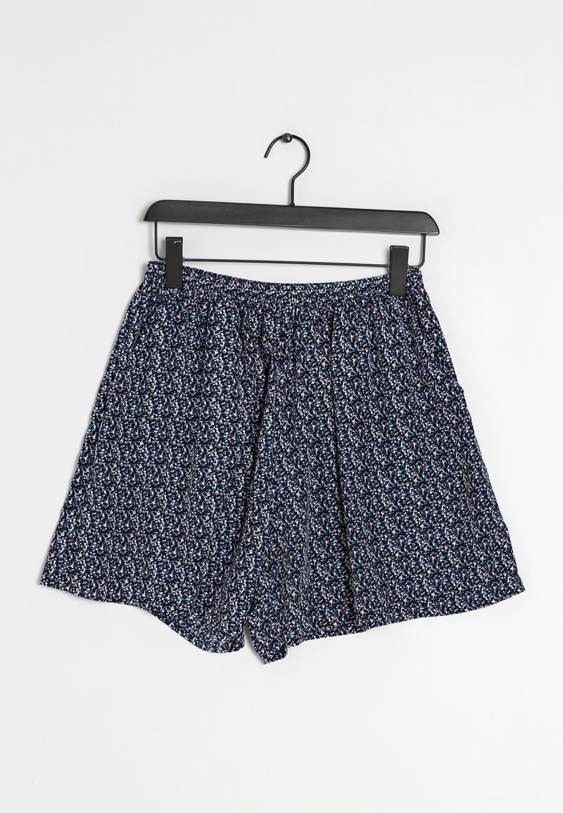 Shorts à motifs bleus sur un cintre noir. Le tissu présente de petites fleurs blanches, rouges et marines, avec une taille élastique.