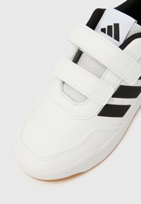 Valge sportking tekstuurse viimistlusega, millel on mustad triibud ja takjakinnitusega rihmad. Hingavad võrgust osad tagavad ventilatsiooni.