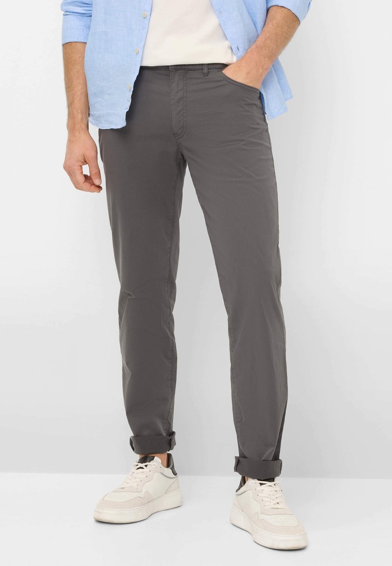 Grijze, lichte chinos met een rechte pijp, voorzien van zijzakken, opgerolde cuffs en gecombineerd met witte sneakers.