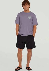 Svijetloplavi T-shirt kratkih rukava s malim grafičkim detaljem na prsima, u kombinaciji s crnim šortsevima i crnim japankama. Ležeran kroj.