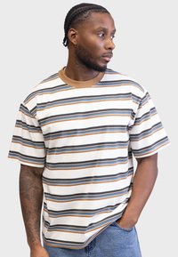 Striped short-sleeve t-shirt in cream, featuring horizontal stripes in brown, blue, and black. Cotton fabric with a round brown neckline.