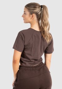 Brun cropped t-shirt lavet af blød bomuld, med korte ærmer og rund hals. Detaljer inkluderer en afslappet pasform og ingen synlige logoer.