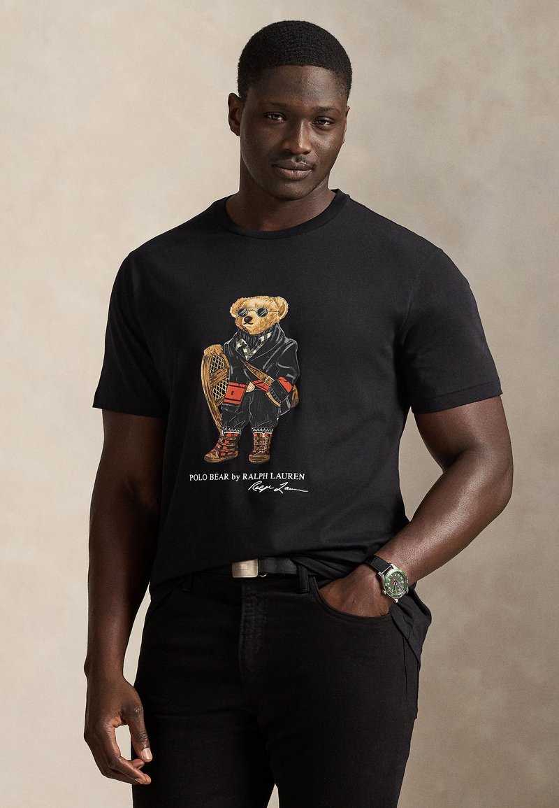 Svart bomulls-T-skjorte med en fargerik bjørnegrafikk i smoking med tilbehør. Brukt med mørke jeans, viser en tettsittende design.