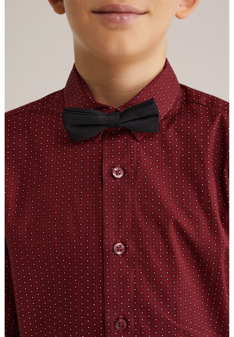 Rood patroonstrik met kleine witte vierkanten, dichtgeknoopt met roze knopen, gecombineerd met een zwarte strik aan de kraag.